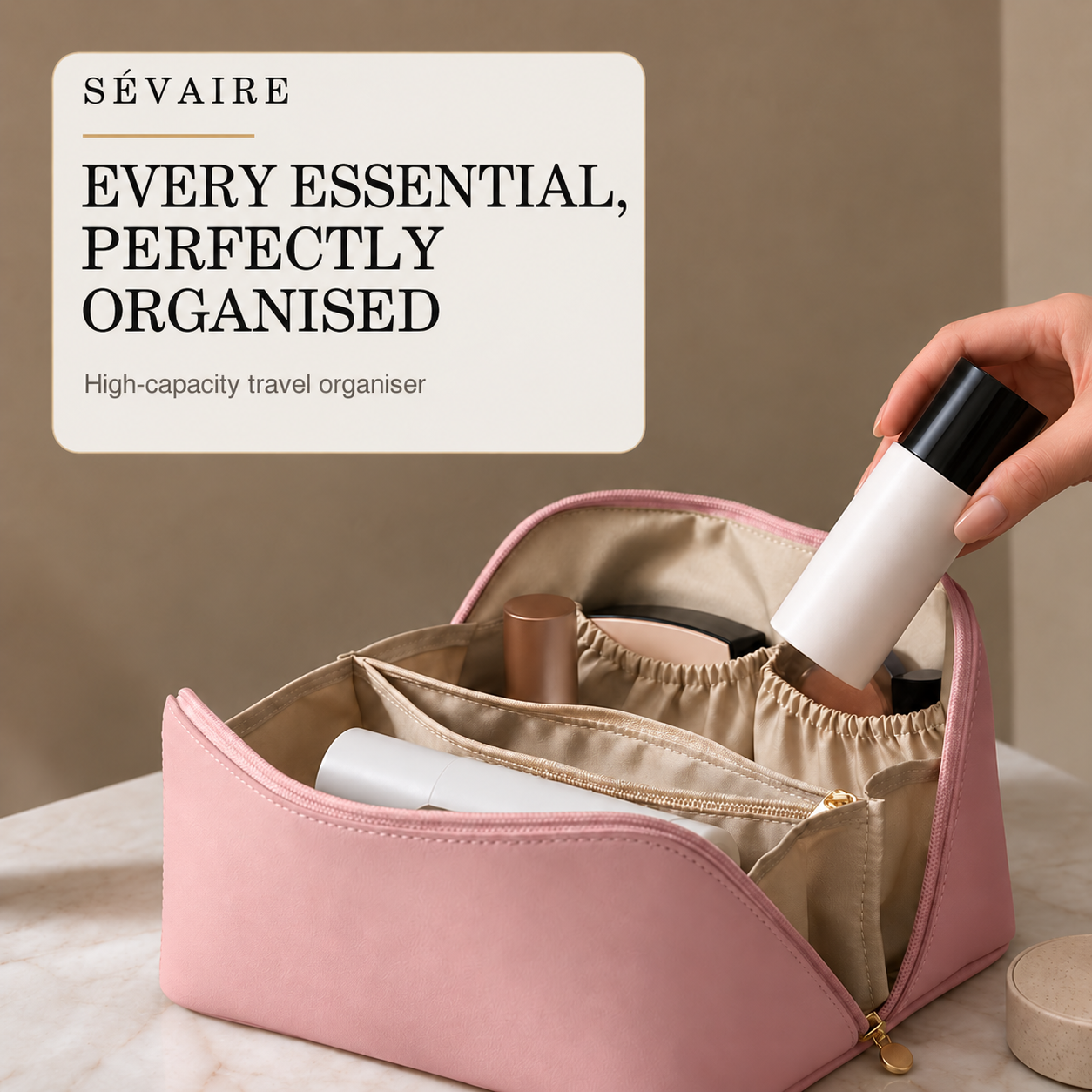 A pink cosmetic bag with a beige interior shown open on a marble surface, with a hand placing a bottle inside. A cream-colored text box at the top left reads 'SÉVAIRE EVERY ESSENTIAL, PERFECTLY ORGANISED'.